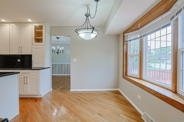 1831 E Camp Mcdonald Rd Unit 0, Mount Prospect, IL 60056 - kitchen with white cabinets, dark countertops, glass insert cabinets, a chandelier, and light wood-style flooring