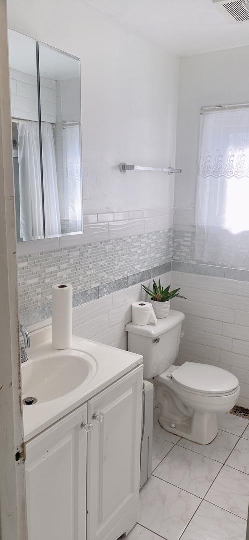 396 Thelma Ct, Wheeling, IL 60090 - bathroom with tile walls, vanity, and marble finish floors