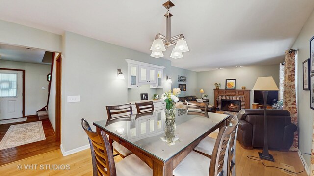2478 Lawson Blvd, Gurnee, IL 60031 - dining room with light wood-type flooring, a fireplace, and a chandelier