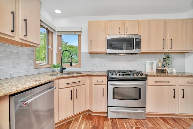 5024 Switch Grass Ln, Naperville, IL 60564 - kitchen with stainless steel appliances, light brown cabinetry, light wood-type flooring, light stone counters, and decorative backsplash