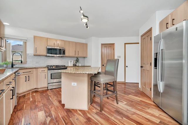 5024 Switch Grass Ln, Naperville, IL 60564 - kitchen with appliances with stainless steel finishes, light brown cabinets, light wood-type flooring, decorative backsplash, and a kitchen bar