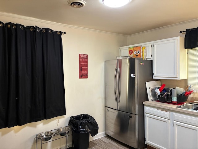 314 Meota St, Park Forest, IL 60466 - kitchen featuring freestanding refrigerator, white cabinetry, light countertops, crown molding, and light wood-style floors