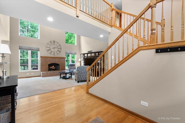 1103 Paul Ct, Fox River Grove, IL 60021 - living room featuring a towering ceiling, stairs, a brick fireplace, wood finished floors, and recessed lighting