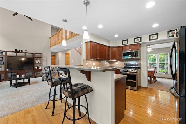 1103 Paul Ct, Fox River Grove, IL 60021 - kitchen with stainless steel appliances, a kitchen bar, light wood finished floors, hanging light fixtures, and ceiling fan