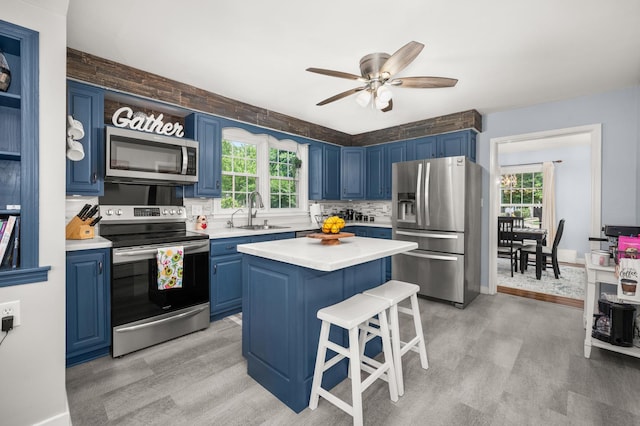 1050 N 8th St, Rochelle, IL 61068 - kitchen with appliances with stainless steel finishes, blue cabinets, light countertops, light wood finished floors, and a kitchen breakfast bar