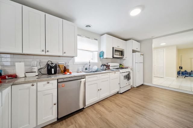 3348 N Narragansett Ave, Chicago, IL 60634 - kitchen featuring stainless steel appliances, light wood finished floors, decorative backsplash, white cabinetry, and recessed lighting