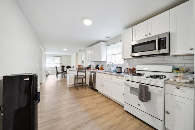 3348 N Narragansett Ave, Chicago, IL 60634 - kitchen featuring appliances with stainless steel finishes, backsplash, light countertops, light wood finished floors, and white cabinetry