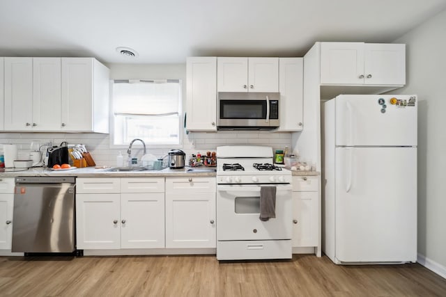 3348 N Narragansett Ave, Chicago, IL 60634 - kitchen featuring appliances with stainless steel finishes, light countertops, white cabinets, and light wood-type flooring
