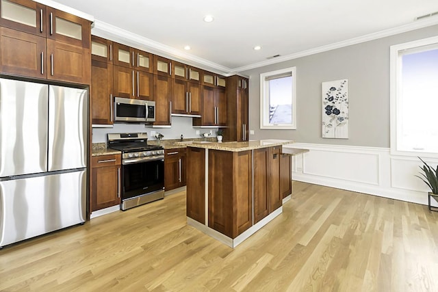 5010 W Lawrence Ave Unit 3B, Chicago, IL 60630 - kitchen with stainless steel appliances, a center island, light wood-type flooring, crown molding, and light stone countertops