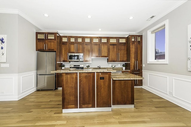 5010 W Lawrence Ave Unit 3B, Chicago, IL 60630 - kitchen with stainless steel appliances, a center island with sink, light wood-style flooring, crown molding, and recessed lighting