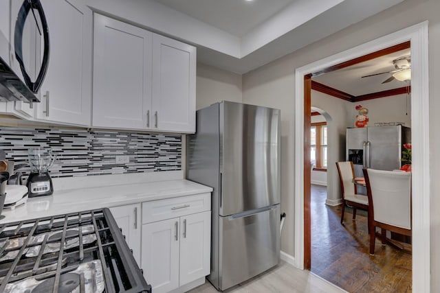 2916 N Melvina Ave, Chicago, IL 60634 - kitchen featuring freestanding refrigerator, black microwave, crown molding, arched walkways, and decorative backsplash