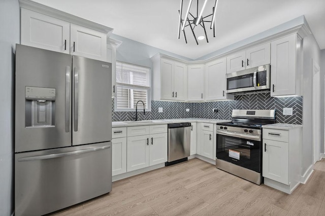 6721 S Ada St, Chicago, IL 60636 - kitchen featuring appliances with stainless steel finishes, light countertops, light wood-style floors, white cabinets, and decorative backsplash