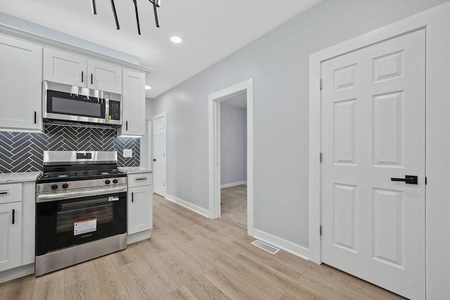 6721 S Ada St, Chicago, IL 60636 - kitchen with appliances with stainless steel finishes, light countertops, decorative backsplash, light wood-style flooring, and white cabinetry