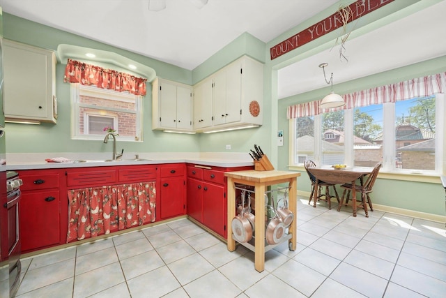 3010 Wisconsin Ave, Berwyn, IL 60402 - kitchen featuring red cabinetry, light countertops, light tile patterned floors, and hanging light fixtures