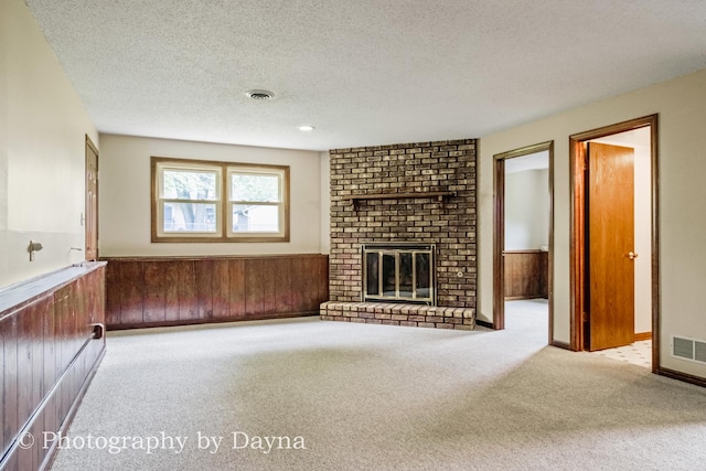 1033 Pheasant Dr, Bradley, IL 60915 - unfurnished living room featuring a wainscoted wall, carpet, wood walls, a textured ceiling, and a fireplace