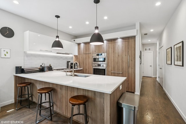 2224 N Seeley Ave Unit 2, Chicago, IL 60647 - kitchen with modern cabinets, brown cabinetry, dark wood-type flooring, a peninsula, and recessed lighting