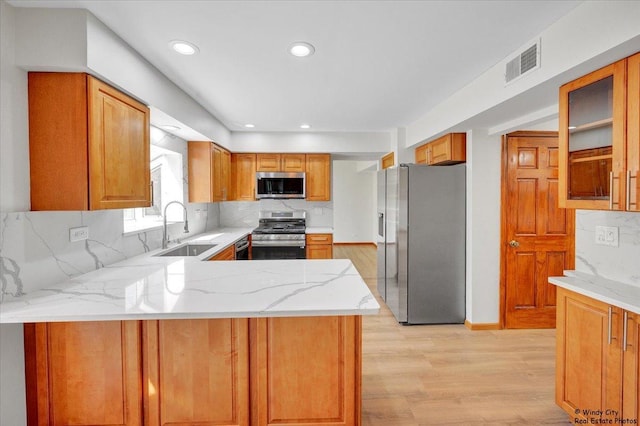 590 Woodcrest Ct, Carol Stream, IL 60188 - kitchen with appliances with stainless steel finishes, light wood finished floors, tasteful backsplash, a peninsula, and light stone counters