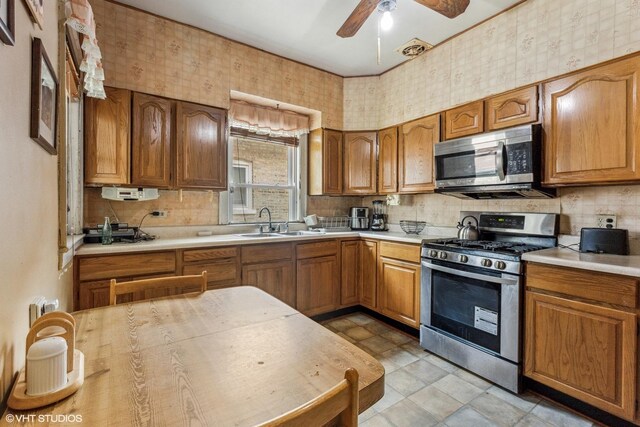 1404 W 97th St, Chicago, IL 60643 - kitchen featuring stainless steel appliances, light countertops, a ceiling fan, brown cabinets, and wallpapered walls