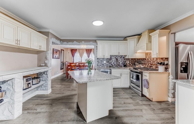 7740 Monitor Ave, Burbank, IL 60459 - kitchen with appliances with stainless steel finishes, custom range hood, ornamental molding, light stone counters, and a kitchen island