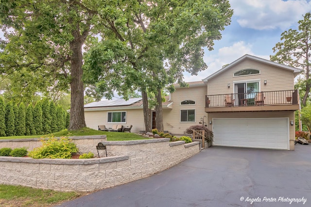 702 W Broadway St, Mchenry, IL 60051 - view of front facade featuring asphalt driveway, a garage, a balcony, and solar panels