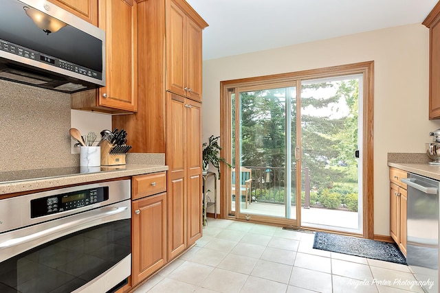 702 W Broadway St, Mchenry, IL 60051 - kitchen with stainless steel appliances, light tile patterned floors, brown cabinetry, and backsplash