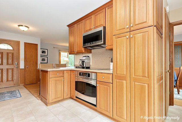 702 W Broadway St, Mchenry, IL 60051 - kitchen with stainless steel appliances, light countertops, a peninsula, and light tile patterned floors