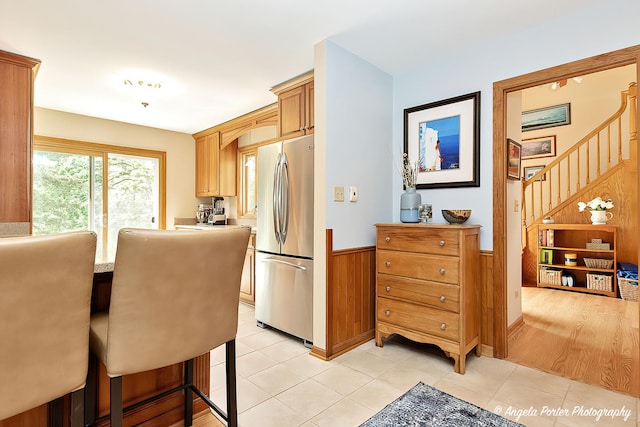 702 W Broadway St, Mchenry, IL 60051 - kitchen featuring stainless steel fridge, a wainscoted wall, light tile patterned floors, wood walls, and light countertops