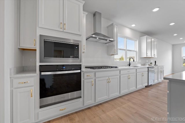 2308 Lawlor Ln, Naperville, IL 60564 - kitchen featuring appliances with stainless steel finishes, wall chimney range hood, light countertops, white cabinets, and light wood finished floors