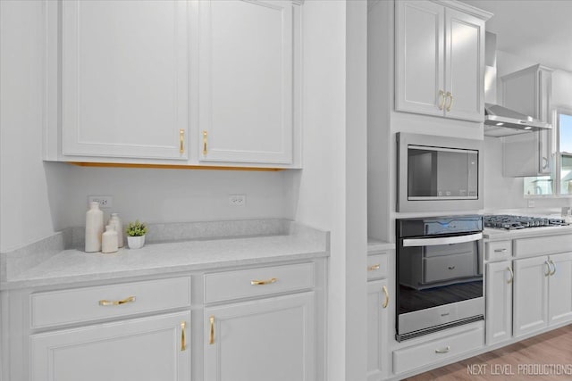 2308 Lawlor Ln, Naperville, IL 60564 - kitchen featuring appliances with stainless steel finishes, white cabinets, wall chimney range hood, and light wood-type flooring