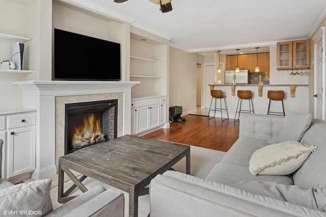 6060 N Ridge Ave Unit 4E, Chicago, IL 60660 - living room with light wood-type flooring, ceiling fan, a tile fireplace, built in shelves, and crown molding
