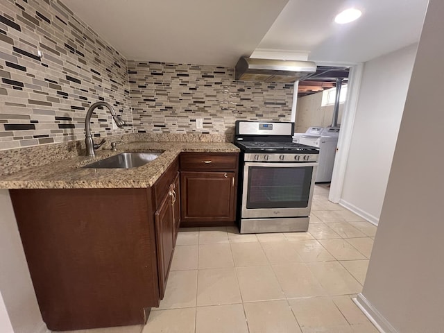 11133 Boeger Ct, Westchester, IL 60154 - kitchen with gas stove, wall chimney exhaust hood, washing machine and clothes dryer, dark brown cabinetry, and decorative backsplash