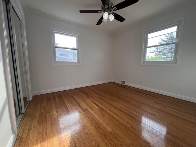 11133 Boeger Ct, Westchester, IL 60154 - unfurnished bedroom featuring multiple windows, light wood-style floors, crown molding, and a ceiling fan