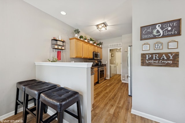 142 W Park Ave Unit C, Sugar Grove, IL 60554 - kitchen with appliances with stainless steel finishes, light wood-type flooring, light brown cabinets, and a breakfast bar area