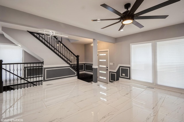 11616 S Lowe Ave, Chicago, IL 60628 - unfurnished living room featuring ceiling fan, a wainscoted wall, marble tiled floors, healthy amount of natural light, and stairway