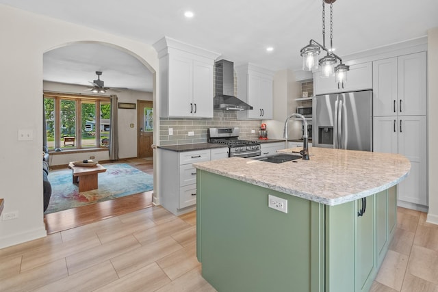277 Mcmillan St, Grayslake, IL 60030 - kitchen with stainless steel appliances, wall chimney exhaust hood, arched walkways, ceiling fan, and white cabinetry