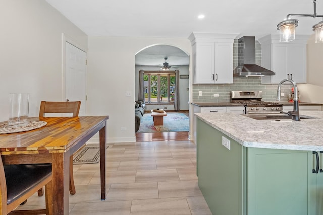 277 Mcmillan St, Grayslake, IL 60030 - kitchen featuring wall chimney exhaust hood, white cabinets, ceiling fan, arched walkways, and tasteful backsplash