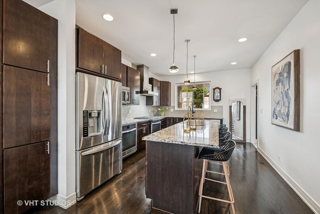 2503 N Maplewood Ave, Chicago, IL 60647 - kitchen with appliances with stainless steel finishes, wall chimney exhaust hood, dark wood finished floors, a kitchen bar, and dark brown cabinetry