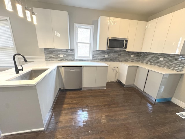 9432 S Vernon Ave, Chicago, IL 60619 - kitchen with appliances with stainless steel finishes, a peninsula, dark wood finished floors, decorative backsplash, and decorative light fixtures