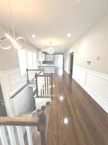 9432 S Vernon Ave, Chicago, IL 60619 - hallway with a decorative wall, wainscoting, dark wood-style flooring, a chandelier, and an upstairs landing