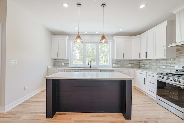 7948 W 74th Ave, Bridgeview, IL 60455 - kitchen with stainless steel gas stove, backsplash, wall chimney exhaust hood, white cabinetry, and light wood-style flooring