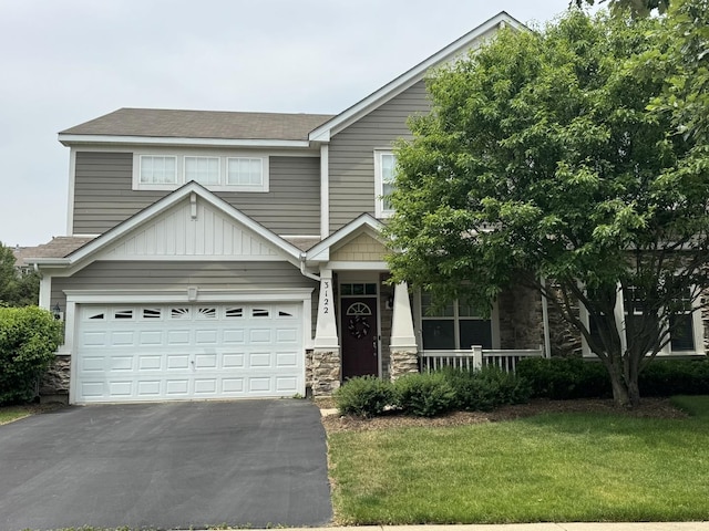 3122 Kyra Ln, Elgin, IL 60124 - view of front facade with driveway, stone siding, a porch, a front lawn, and a shingled roof