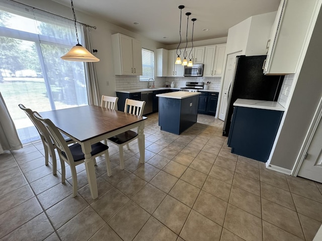 3122 Kyra Ln, Elgin, IL 60124 - kitchen with stainless steel appliances, a kitchen island, tasteful backsplash, light tile patterned floors, and light countertops
