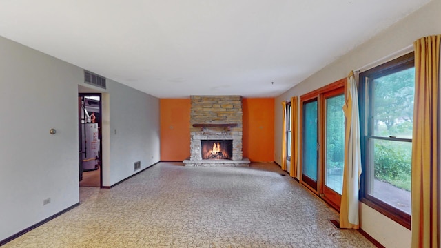 198 S Circle Ave, Bloomingdale, IL 60108 - unfurnished living room with healthy amount of natural light, a stone fireplace, and water heater