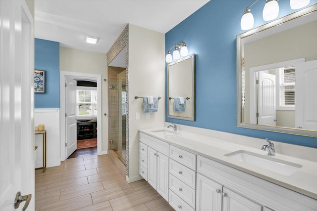 2955 E Stone Creek Blvd, Urbana, IL 61802 - bathroom with double vanity, a shower stall, wood finished floors, and wainscoting