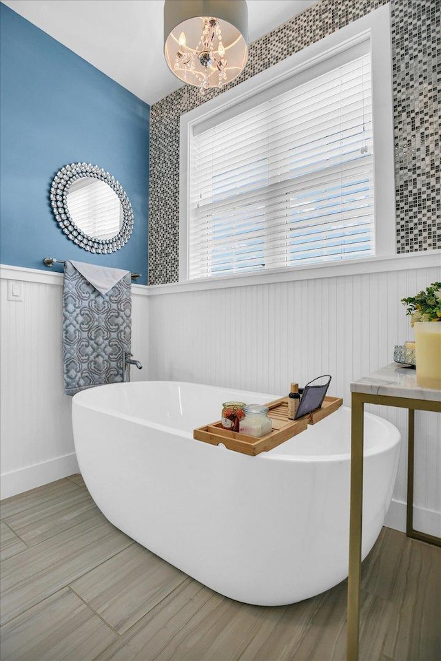 2955 E Stone Creek Blvd, Urbana, IL 61802 - full bathroom with a wainscoted wall, a freestanding tub, a chandelier, and wood finished floors