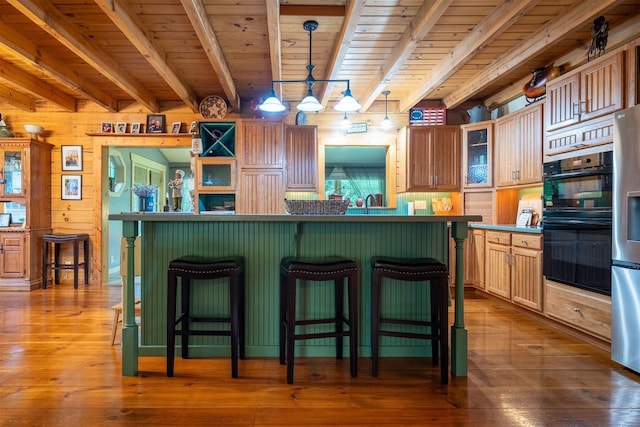 13153 E 1920 N Rd, Pontiac, IL 61764 - kitchen with a wood ceiling with exposed beams, a breakfast bar, dark wood-type flooring, glass insert cabinets, and wooden walls