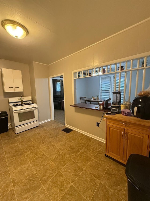 kitchen featuring white gas stove and white cabinets