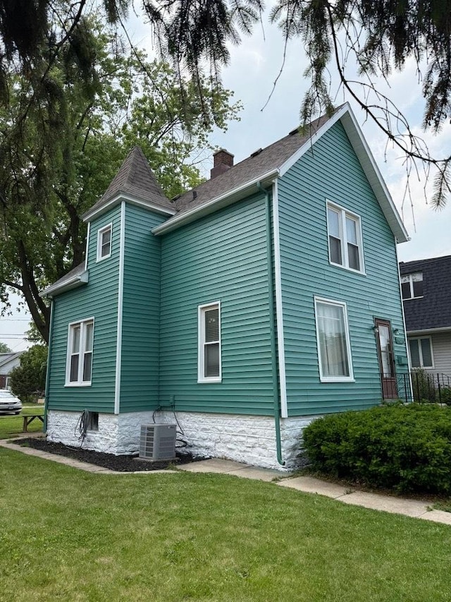view of side of home with a chimney and a lawn