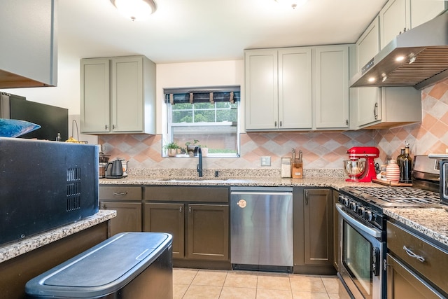 2417 Lyons St, Evanston, IL 60201 - kitchen featuring appliances with stainless steel finishes, under cabinet range hood, backsplash, light tile patterned flooring, and light stone countertops