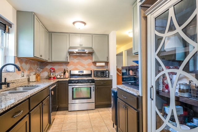 2417 Lyons St, Evanston, IL 60201 - kitchen with gas range, under cabinet range hood, backsplash, light tile patterned floors, and light stone countertops